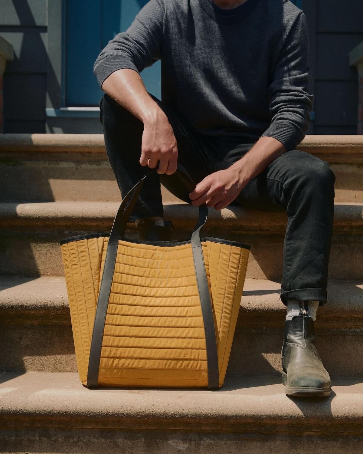 Man wearing boots sitting down with Arris Tote