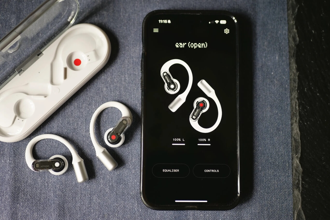 Nothing Earbuds Open next to a phone showing the Nothing app